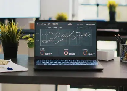 Business Graphs and Figures on Laptop Left Open on Desk in Empty Office